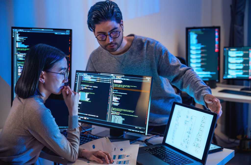 3635168-0-33880100-1742244038-shutterstock_2441844605-1 asian and Indian Developer devops team discussion about coding program with software computer at night in office