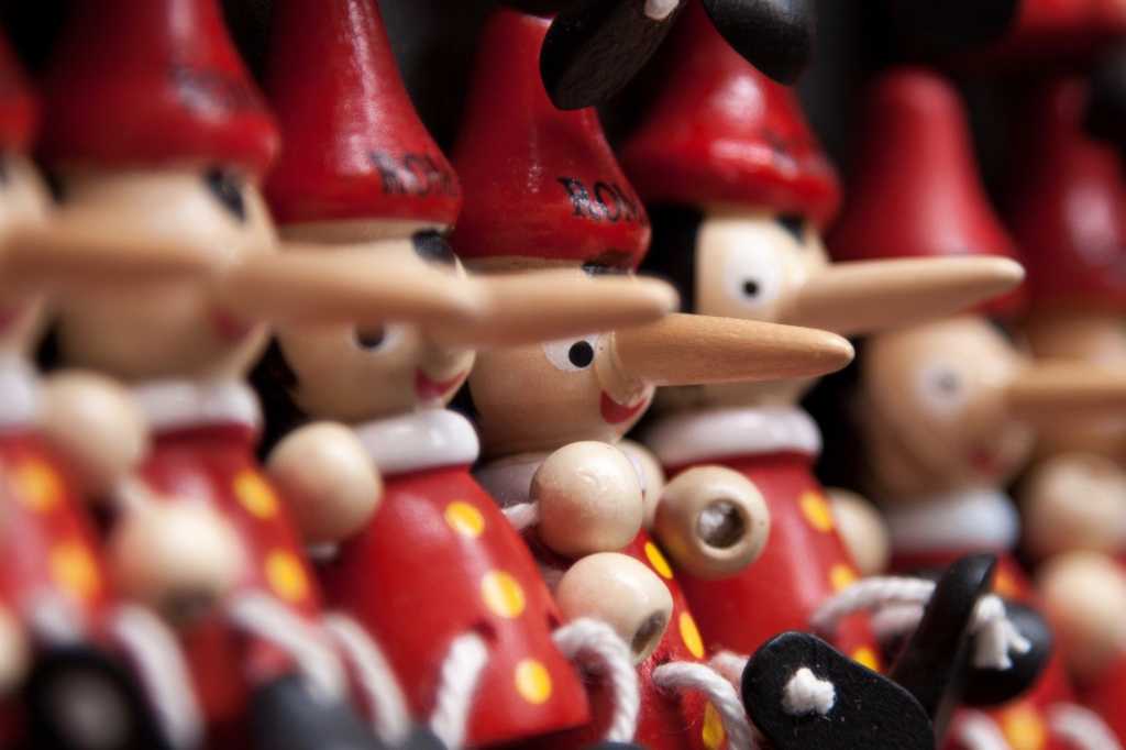 3809889-0-50366900-1737837400-pinnochio-100656392-orig-1 close up view of wooden puppets Pinochios with long noses red hats white collars red shirts with yellow buttons
