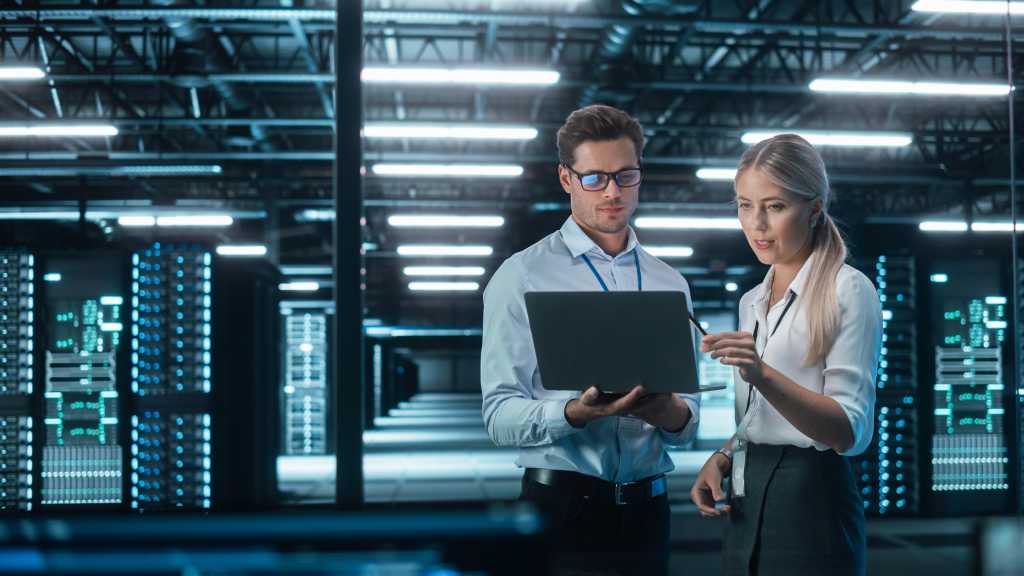 3818889-0-13327500-1739461196-shutterstock_2136788109-1 Male and Female Programmers Talking about Work, Solving Problems Together, Using Laptop Computer. Software Development Code Writing Website Design Database Architecture Concept