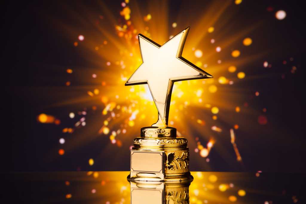 3831686-0-15490000-1740560565-shutterstock_261883238-1 Gold star sits on a pedestal throwing sparks against a dark background.