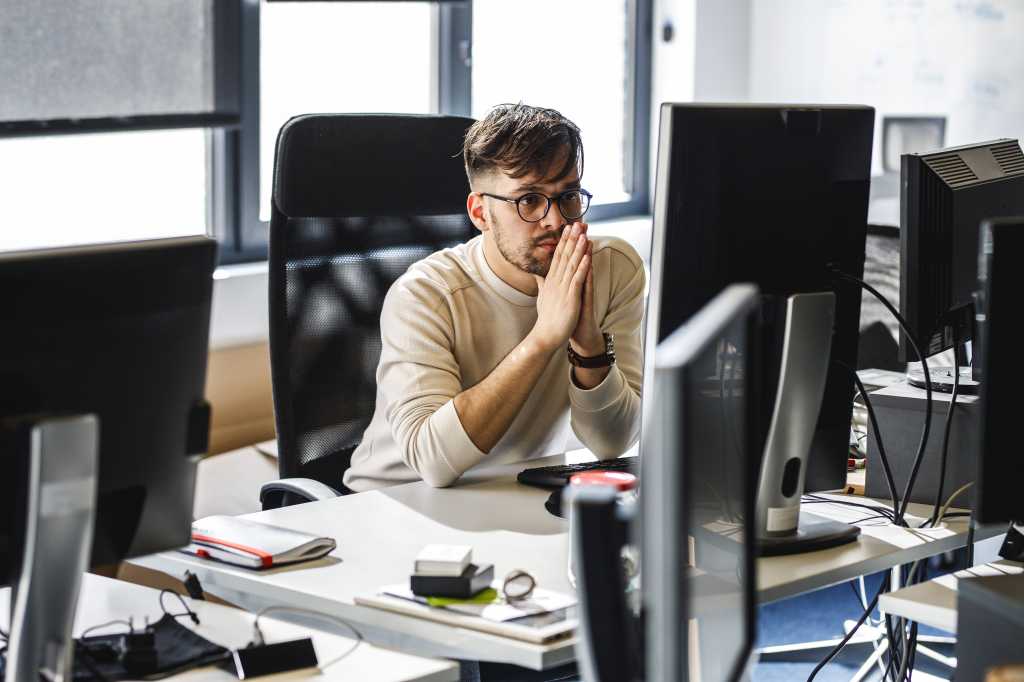 3839280-0-15145800-1742202072-shutterstock_1918271222-100961377-orig-1 Programmer sitting at the desk in his office and trying to solve problem of new code.