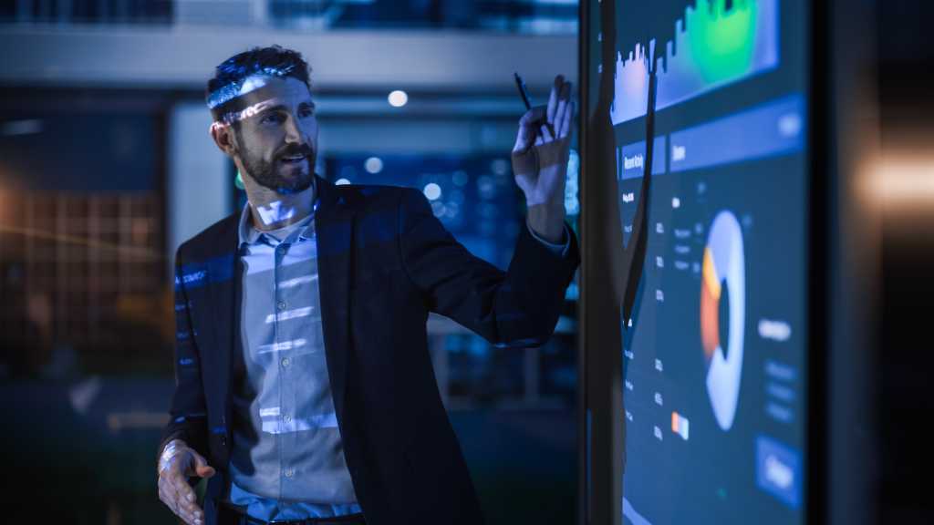 3583473-0-88528000-1738742934-shutterstock_2140347409-1 Conference Business Meeting Presentation: CEO Businessman Shows Data to Group of Investors, Businessspeople. Projector Screen Shows Graphs, Product Sales, Revenue Growth Strategy, e-Commerce Analysis