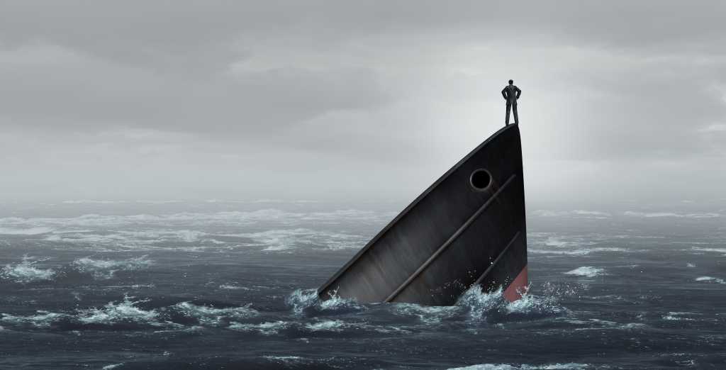 3596771-0-47646400-1730671164-shutterstock_1919350124-1 Sinking ship metaphor and failing business despair concept as a stranded businessman lost at sea as a failed corporate idea for financial crisis or being lost with 3D illustration elements.
