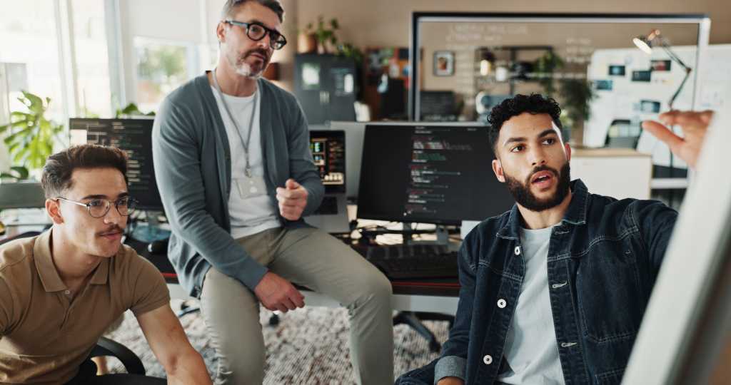 3831759-0-43660300-1740538362-shutterstock_2546315975-1 Programmer, teamwork and planning with business people in office for website developer, coding bootcamp and review. Mentor, collaboration and software engineer with group of employees in tech startup