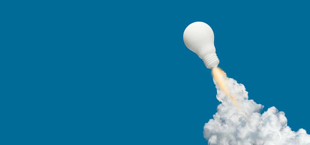 3952000-0-94880200-1743879056-shutterstock_1438292462-1 white light bulb blasts off like a rocket trailing fire and smoke against a blue background