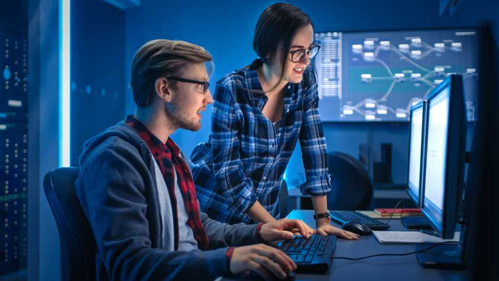 3959533-0-78823500-1744383267-shutterstock_1590824884-1 Male and Female Programmers Talking, Solving Problem, Using Computers, Doing High Five After Success. Software Development / Code Writing / Website Design / Database Architecture. Technical Department