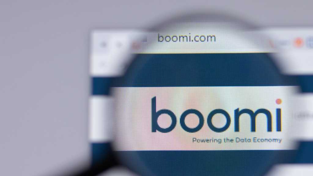 3985651-0-09228800-1747238555-boomi-website-1 A photograph of a monitor displaying Boomi's website, with a magnifying glass hovering over the company's logo.