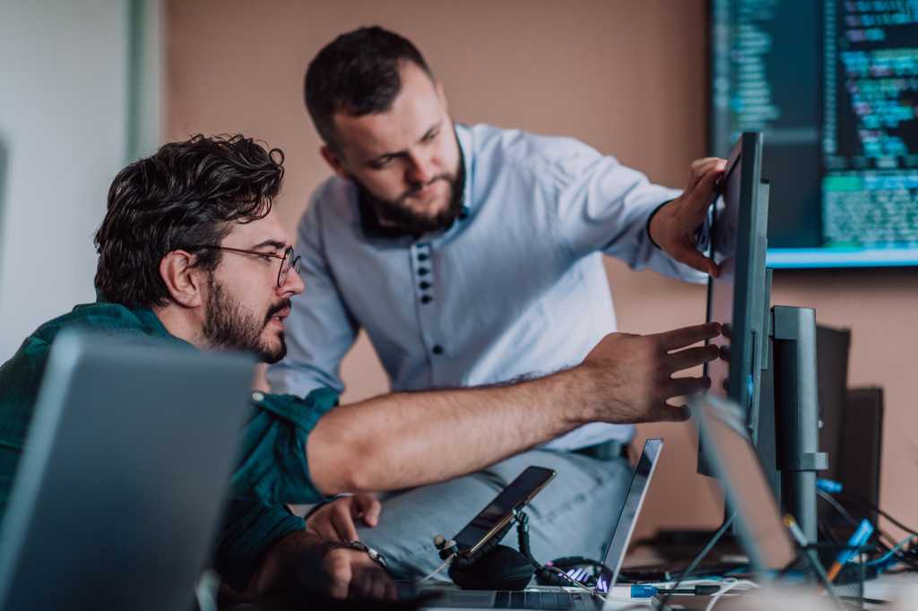 3993538-0-54507700-1749158468-shutterstock_2311984335-1 Programmers engrossed in deep collaboration, diligently working together to solve complex problems and develop innovative mobile applications with seamless functionality.