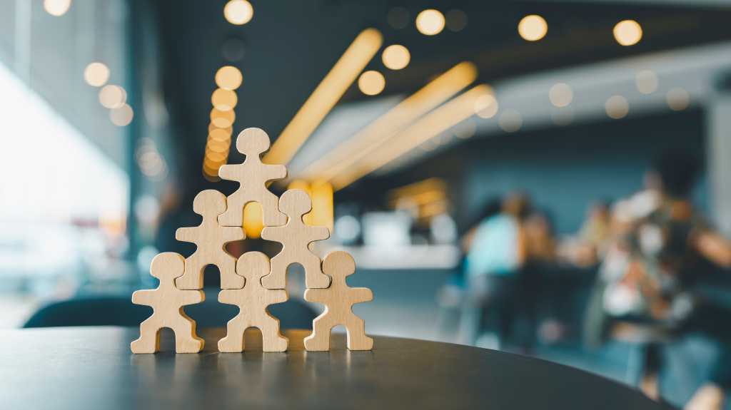 4006991-0-88729500-1750275074-shutterstock_2494119625-1 Human-figure cutouts arranged in a standing pyramid formation. Teamwork.